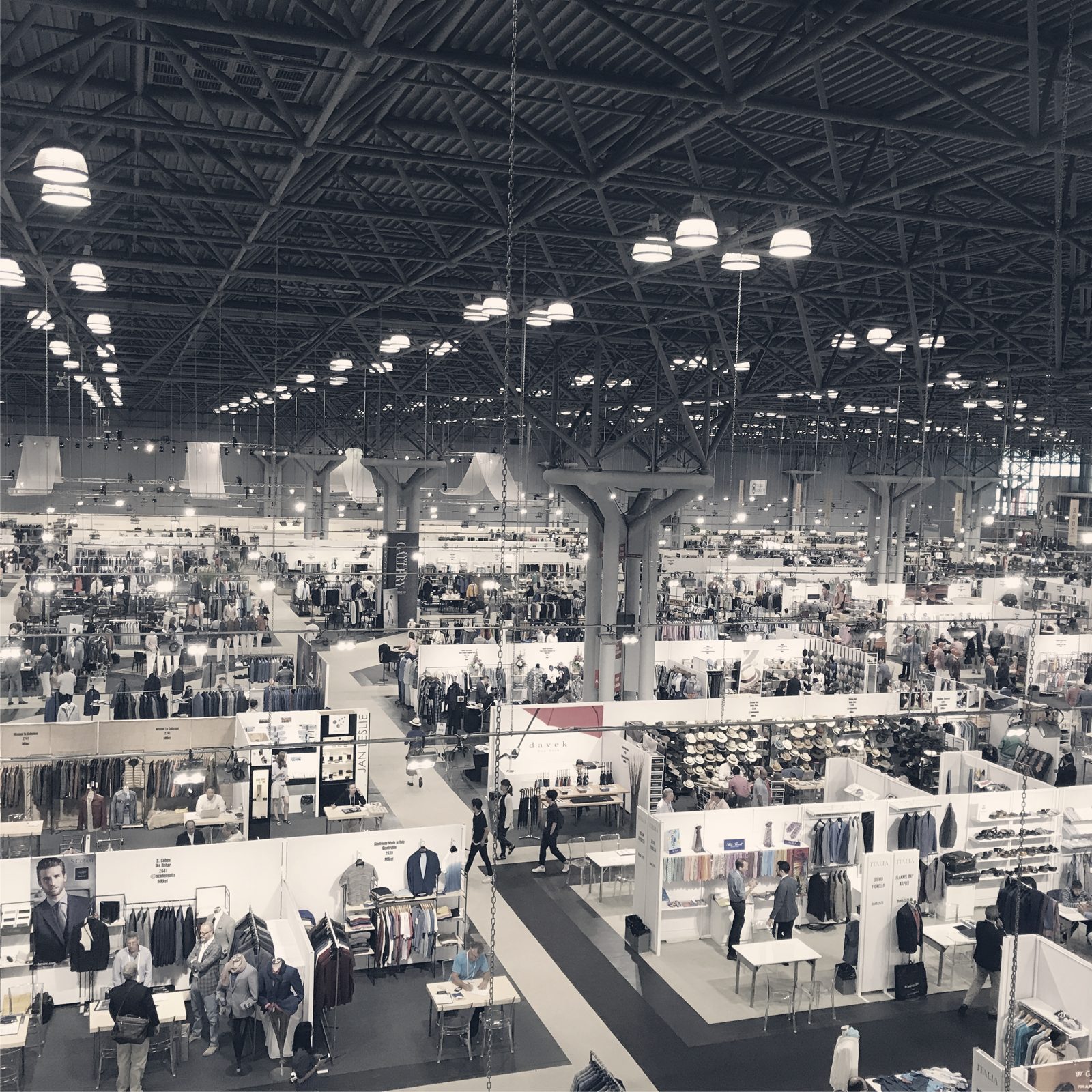 A trade show floor in New York during market week, seen from above: rows of booths, racks and buyers